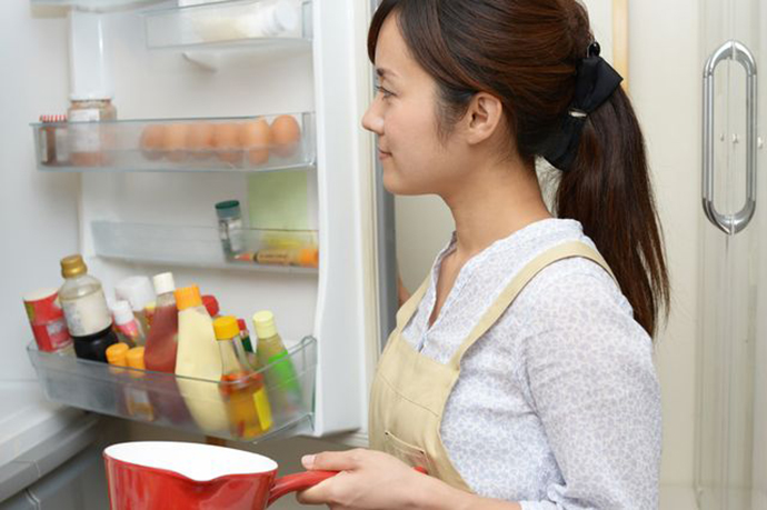 お鍋片手に冷蔵庫を開ける女性