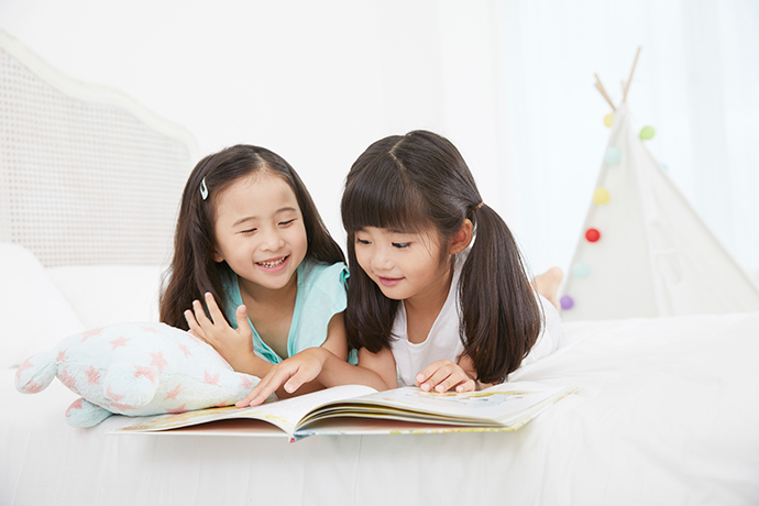 部屋で本を読む女の子2人