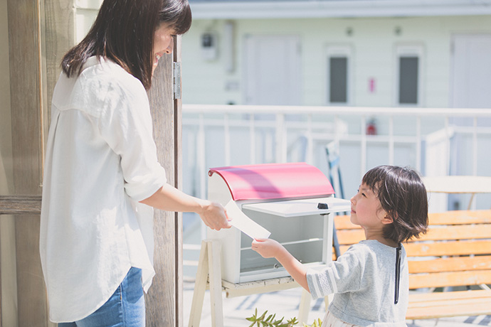 ポストから郵便物を母親に渡す子ども