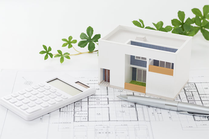 住宅設計図と家の模型、電卓、ペン