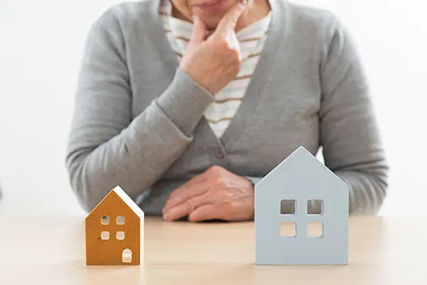 2つの住宅と悩む男性