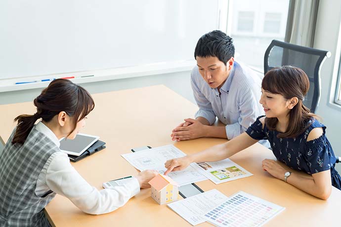 話し合う夫婦と女性と家の模型